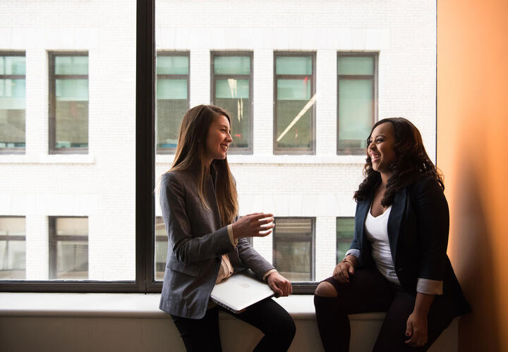 two women chatting by a window. image credit: Christina Wocintechchat/Unsplash